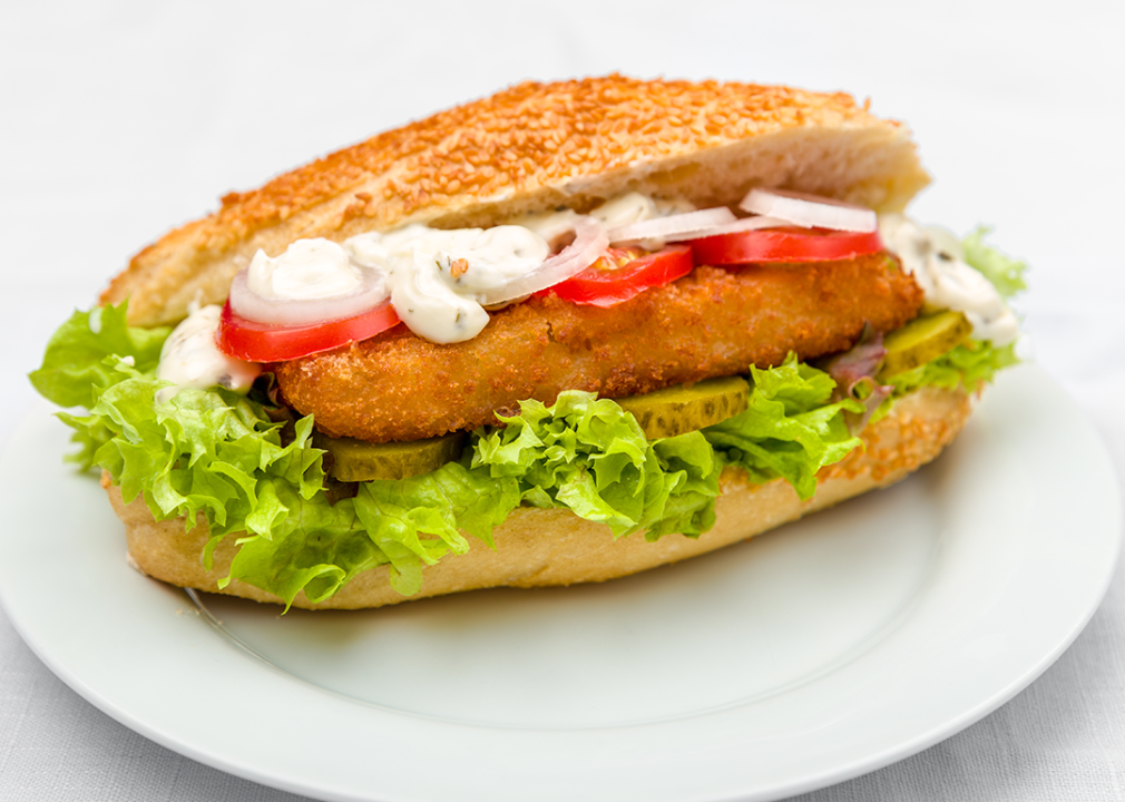 Fried fish on a bun with lettuce, tomato and cucumber.
