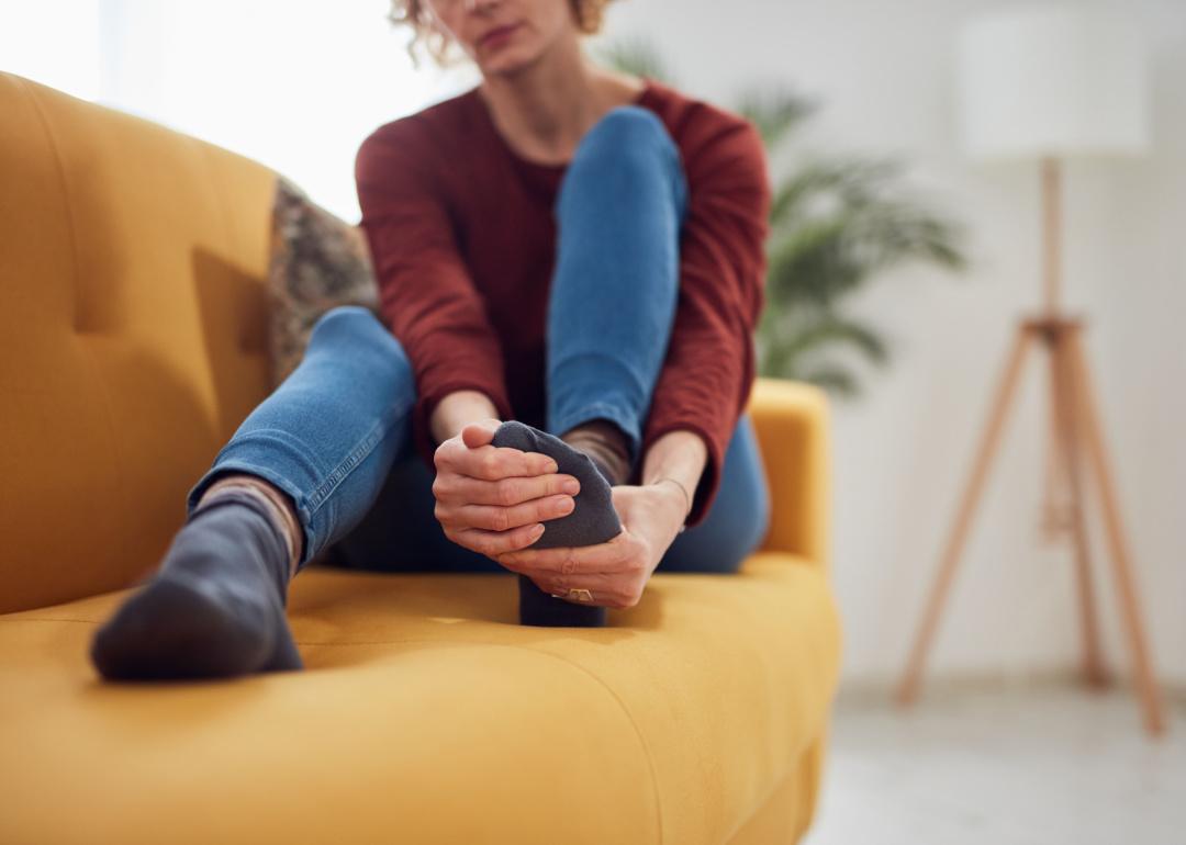 Woman on couch holding foot.