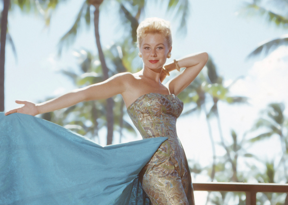 Mitzi Gaynor poses in glamorous gown by palm tress for the 1958 film version of 'South Pacific'.