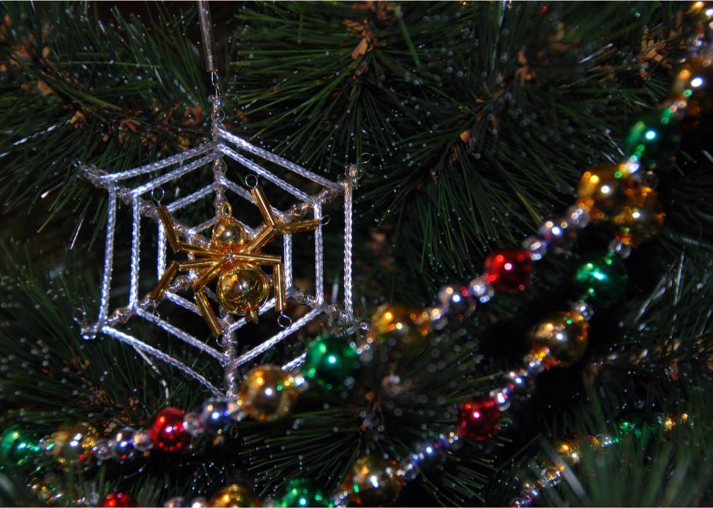 A close up of a gold spider and silver web ornament on a Christmas tree.