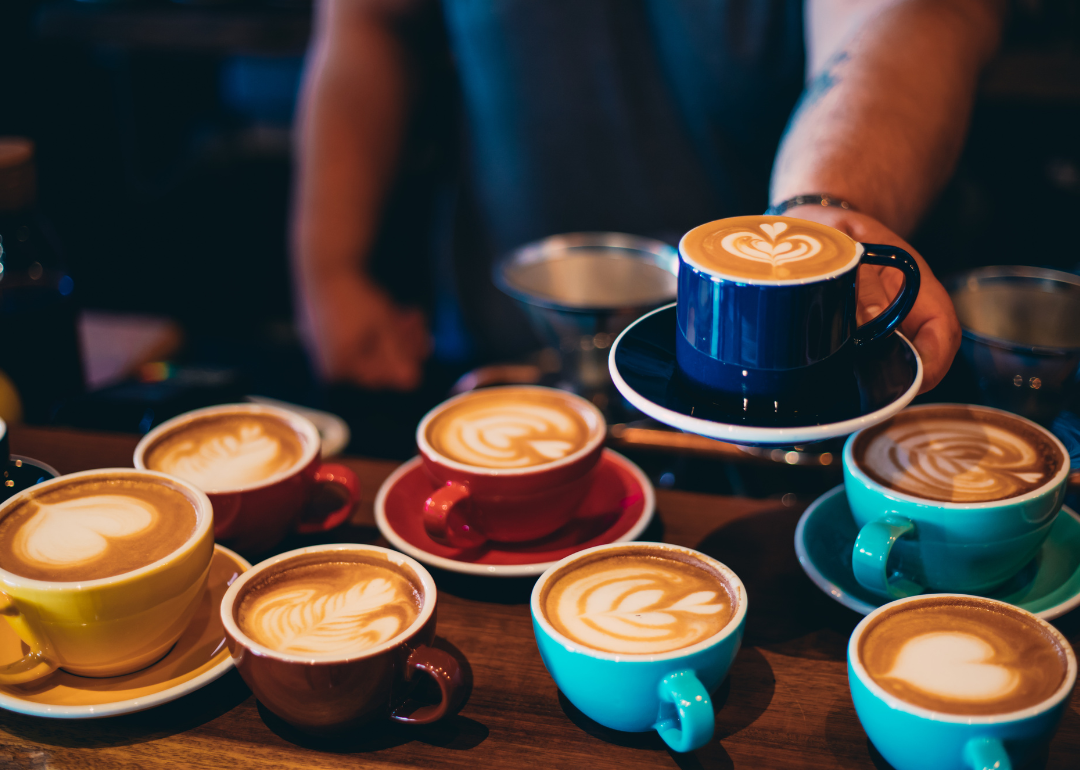 Barista serving latte in blue cup.