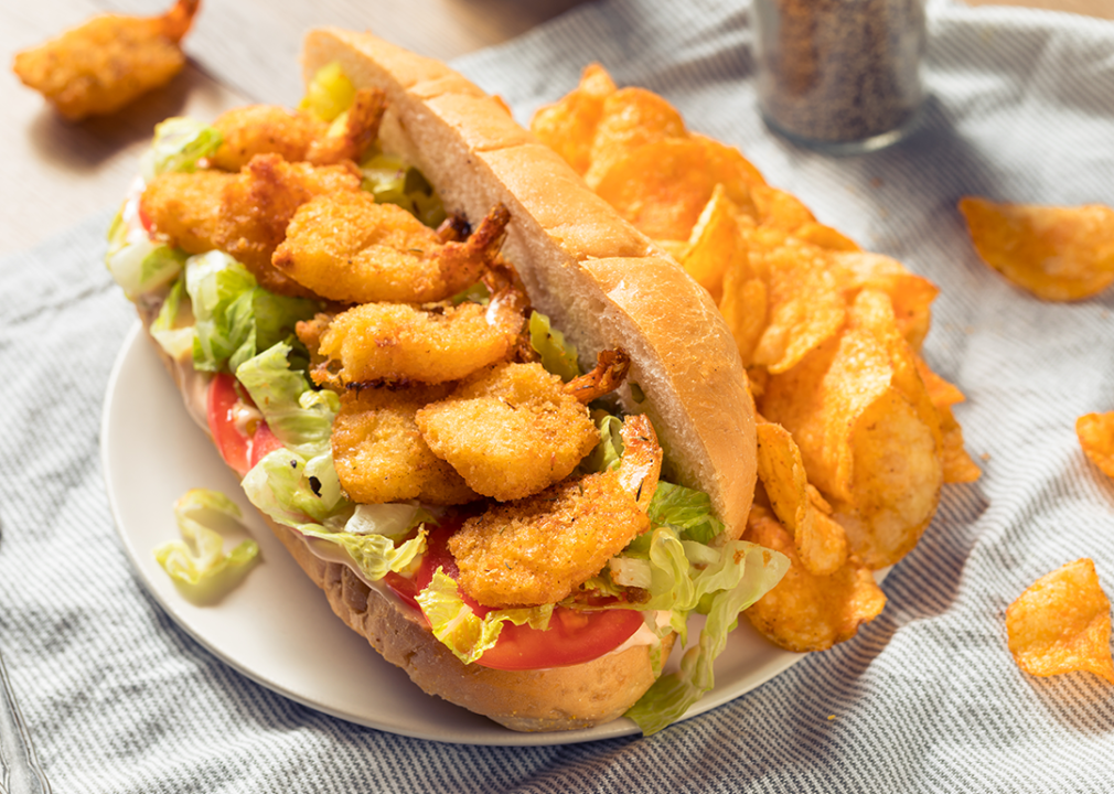 Shrimp po'boy sandwich with lettuce and tomato on plate.
