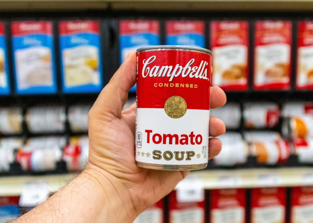 Hand holding can of Campbells Tomato soup.