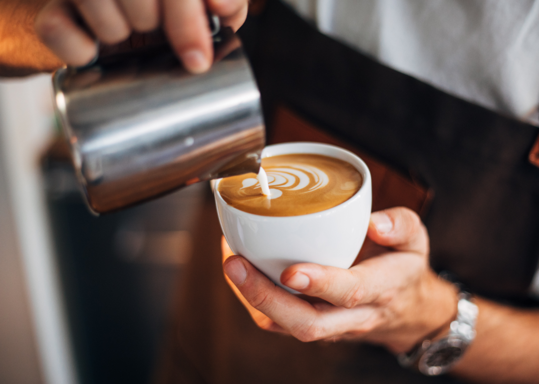 Barista pouring latte drink.