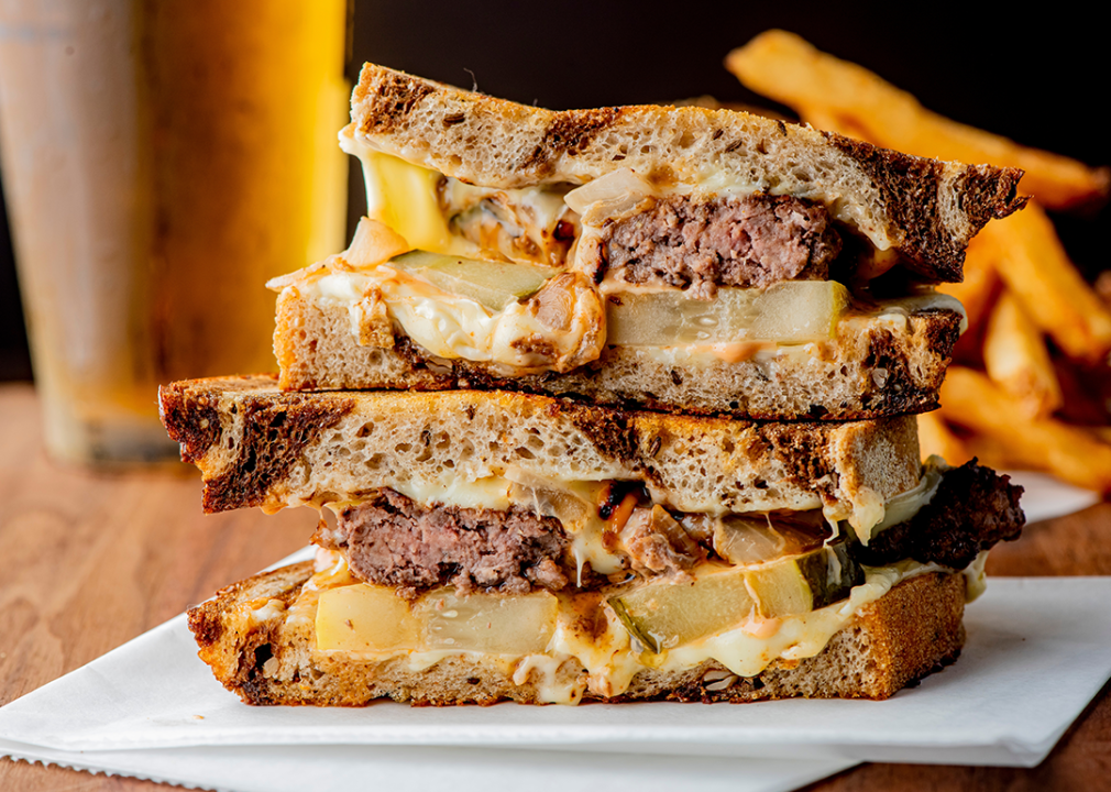 Ground beef patty with melted cheese and topped with caramelized onions on two slices of griddled rye bread.