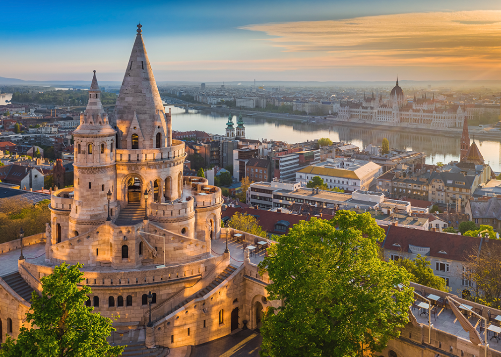 Fisherman's Bastion and green trees. Parliament of Hungary and River Danube a