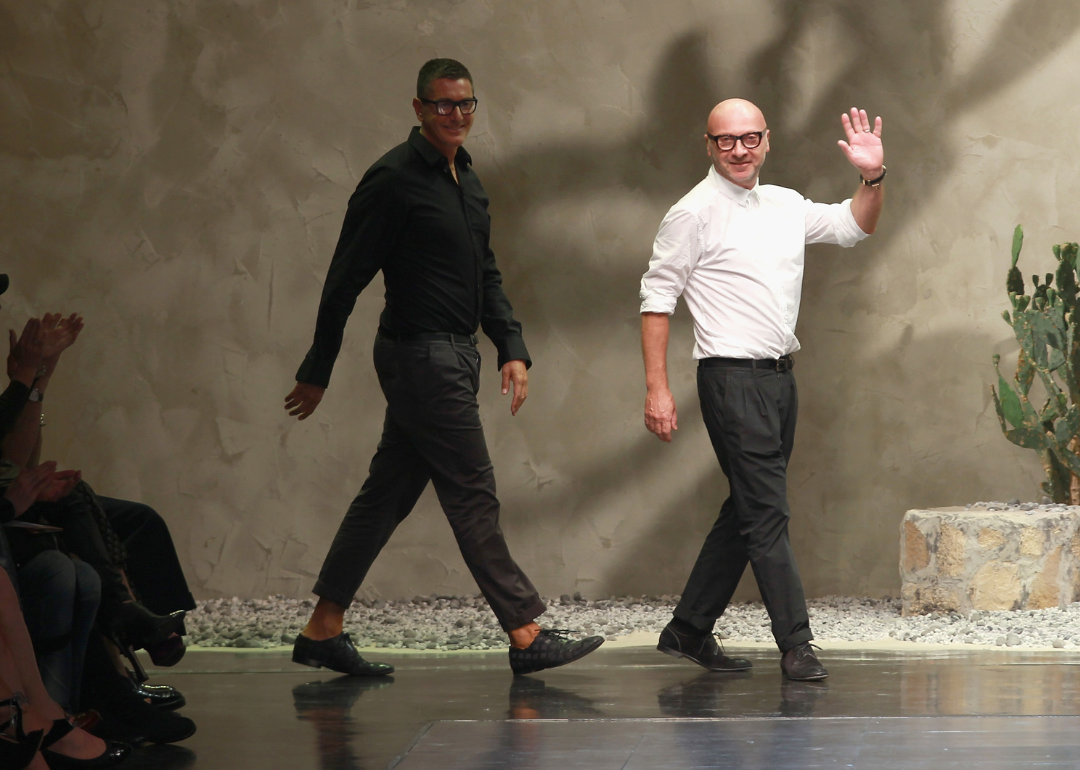 Domenico Dolce and Stefano Gabbana wave from runway at fashion show.