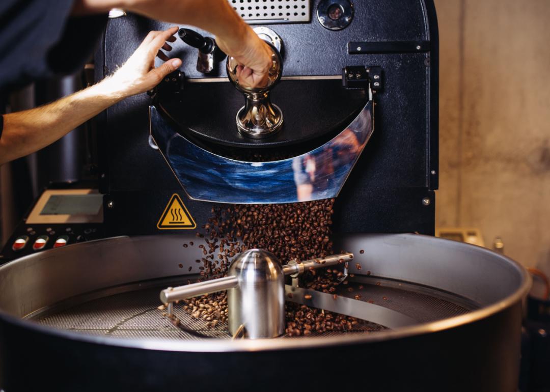 Roaster pouring freshly roasted coffee into cooling tray.