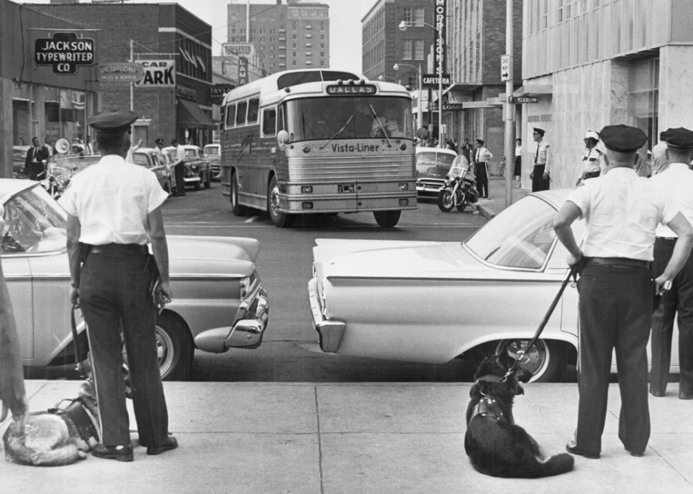 As a Trailways bus carrying Freedom Riders arrives in Jackson, Mississippi on May 24, 1961, police officers with dogs prepare to arrest and jail those on board.