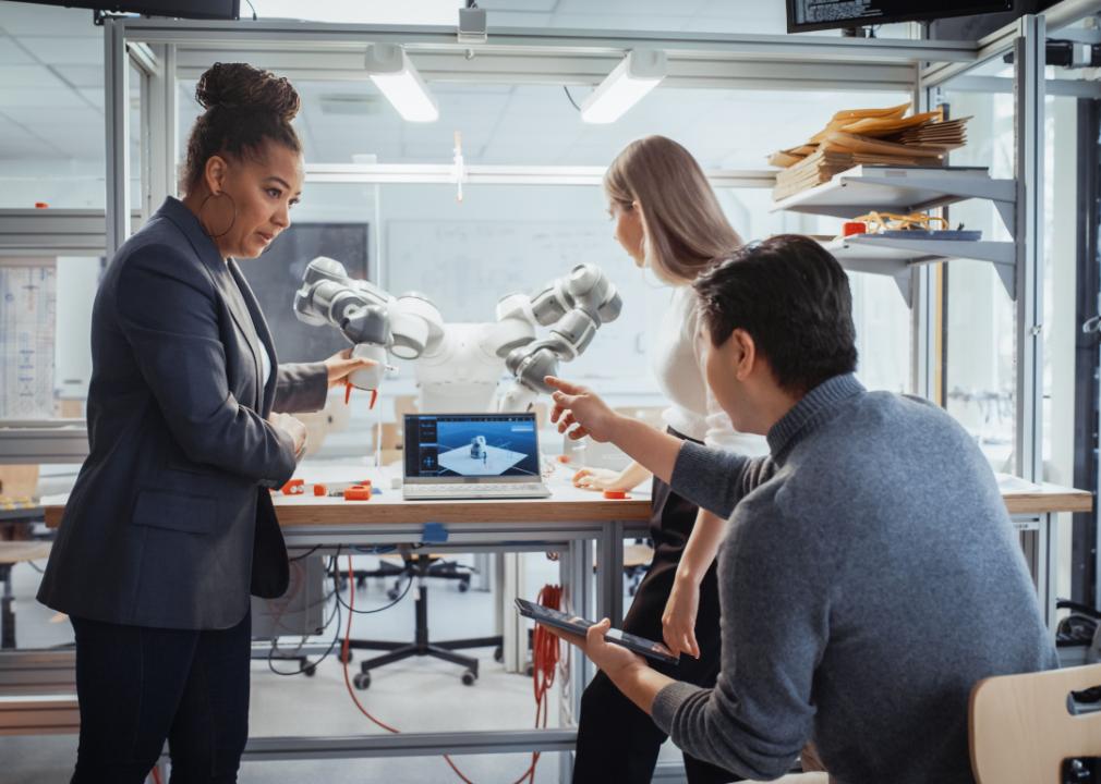 Engineering professor works with students on robot arm.