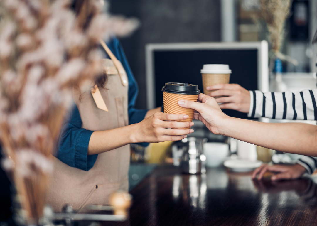 Barista handing customer coffee drink.