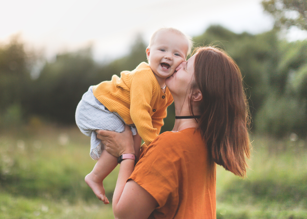 Mother holding baby in park.