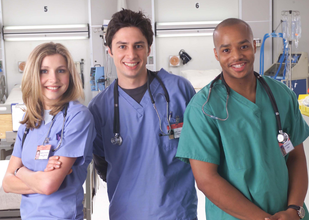 Sarah Chalke, Zach Braff, and Donald Faison pose for a publicity photo wearing scrubs.