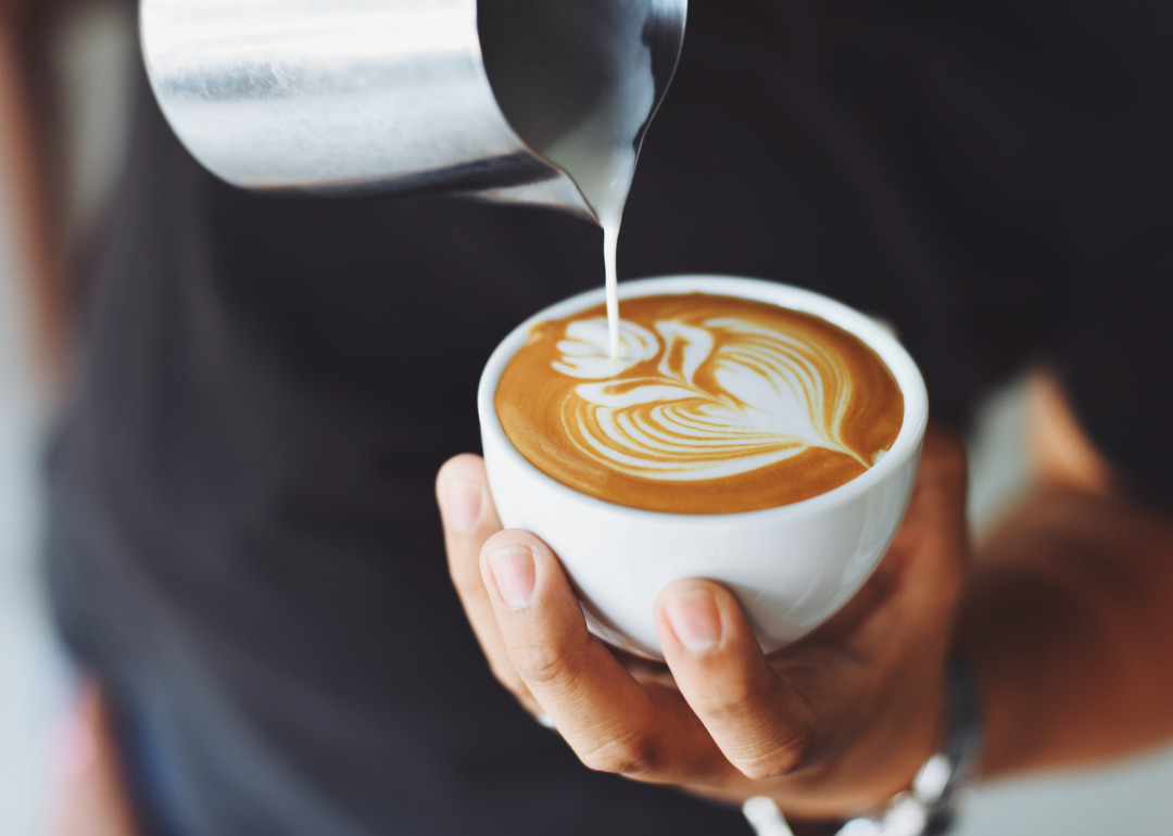 Barista pouring latte drink.