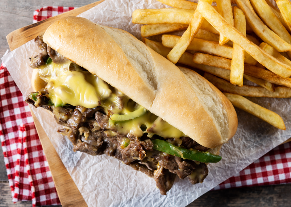 Cheesesteak sandwich with beef, cheese, green peppers and caramelized onions with fries.