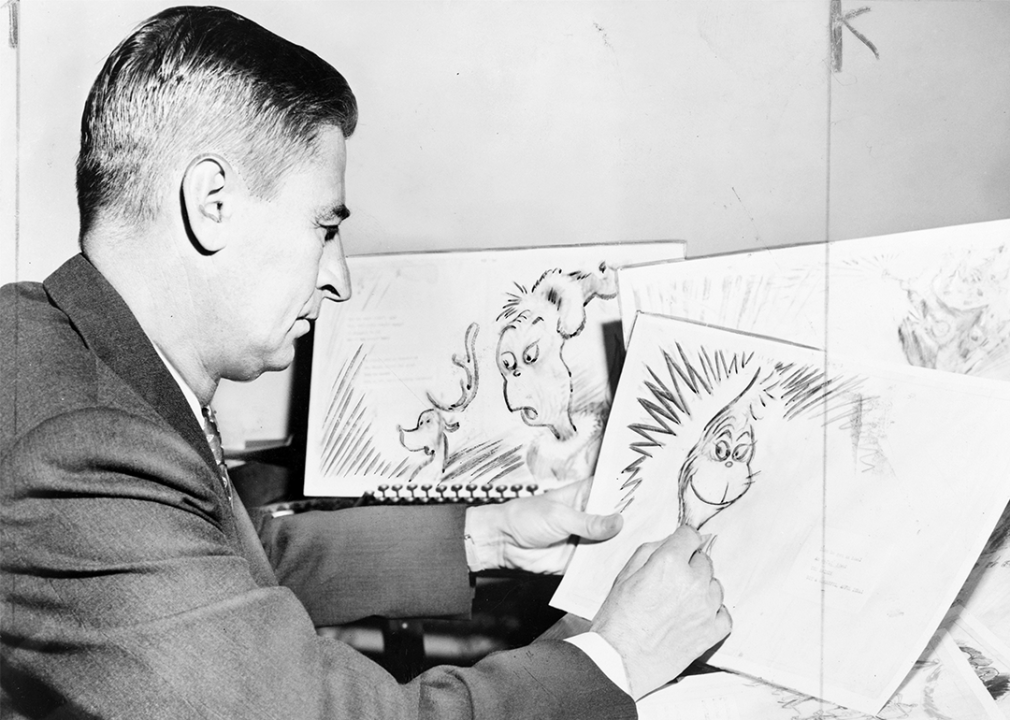 Dr. Seuss Geisel holding illustrations for his book, How the Grinch Stole Christmas.