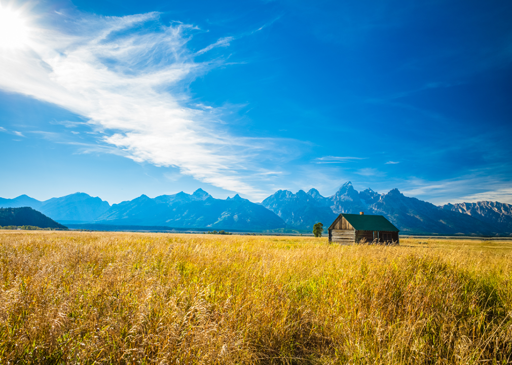Wyoming: Teton County Golden grass prairie and barn with Grand Teton Mountains.