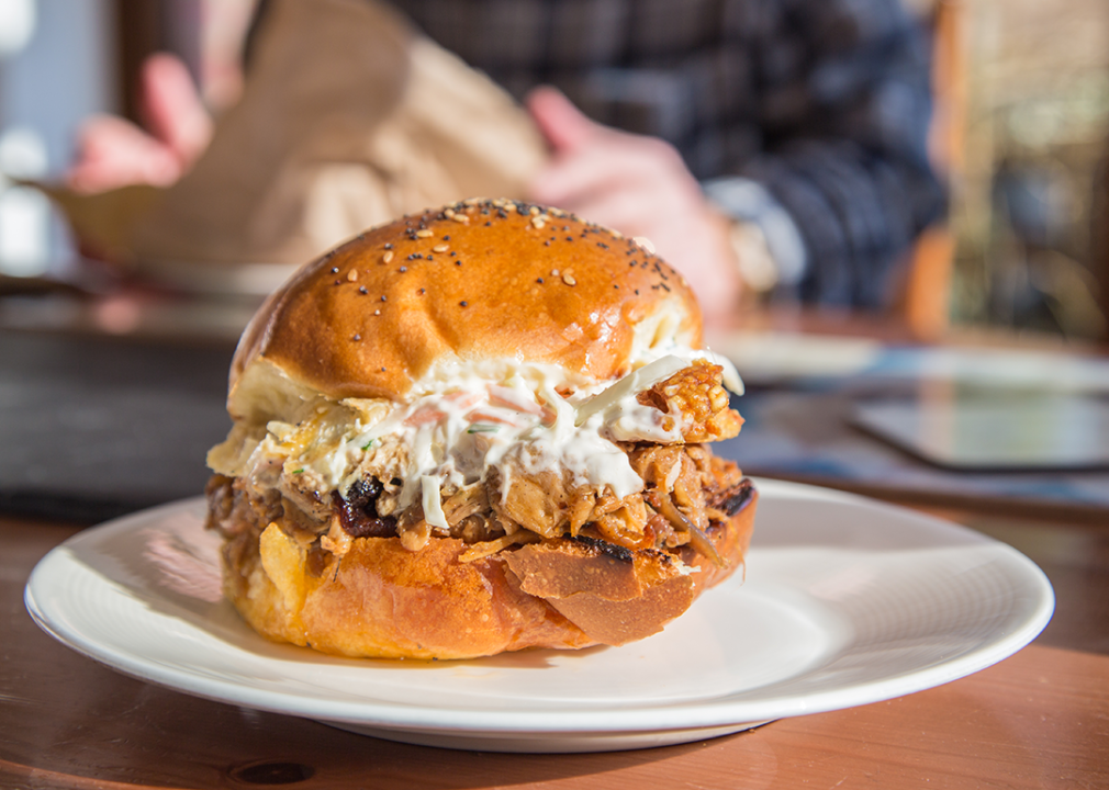 Pulled pork with coleslaw sandwich on a plate.