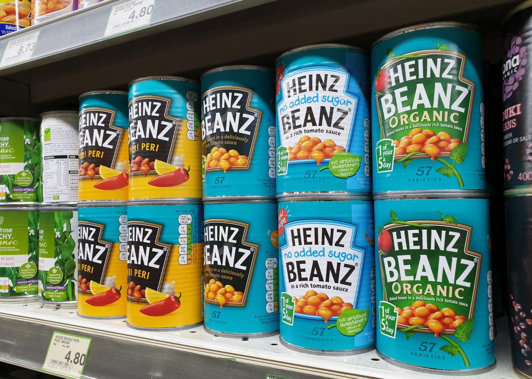 Cans of Heinz Baked Beanz on grocery store shelf.