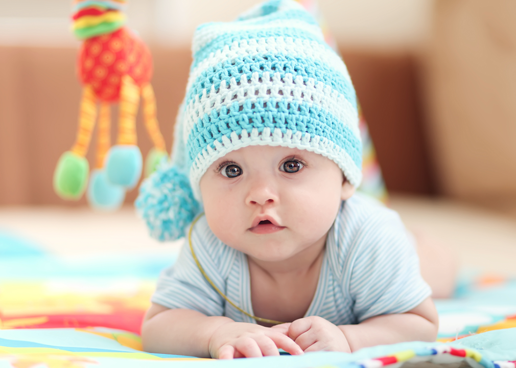 Baby laying on tummy wearing knit hat.