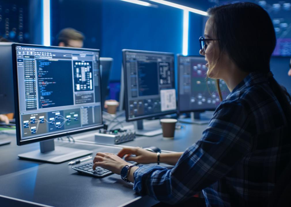 Information technology programmer working on desktop computer in control room.