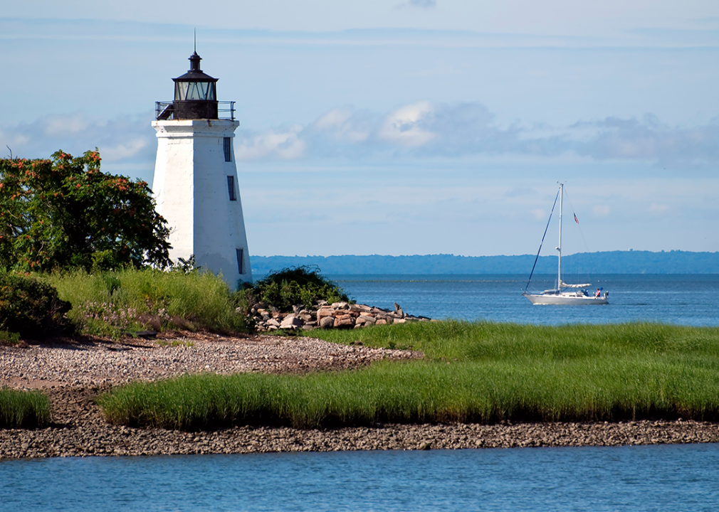 Sailboat passing by tower of Black Rock Harbor lighthouse.