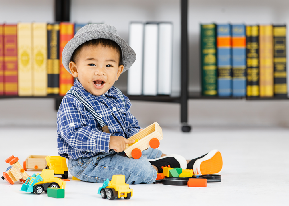 Baby wearing hat playing with wooden toys.