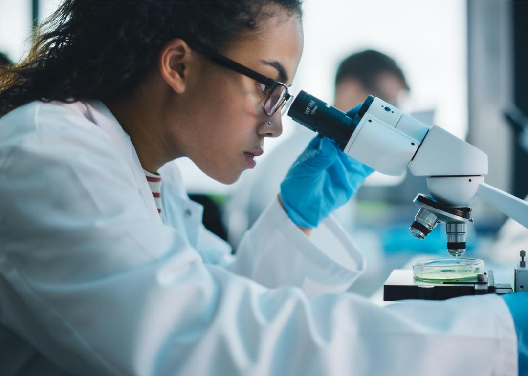 Lab professional looking through microscope.
