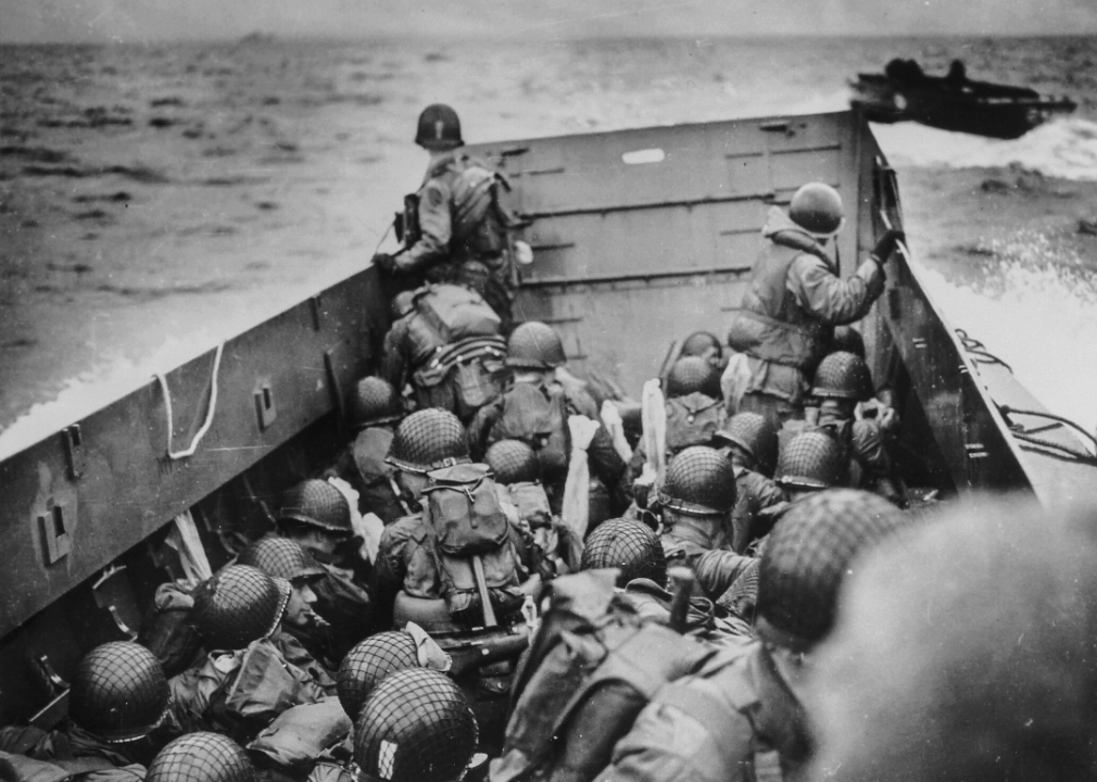Soldiers crouch behind the bulwark of a Coast Guard landing barge as they cross the English Channel on June 6, 1944.