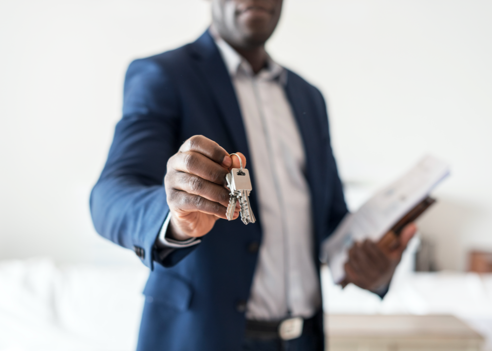 A real estate agent's hand holds out a set of keys.