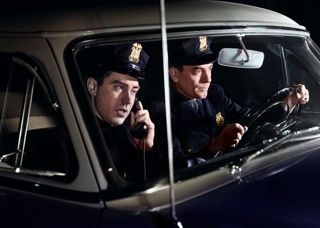 Policemen driving at night in patrol car.