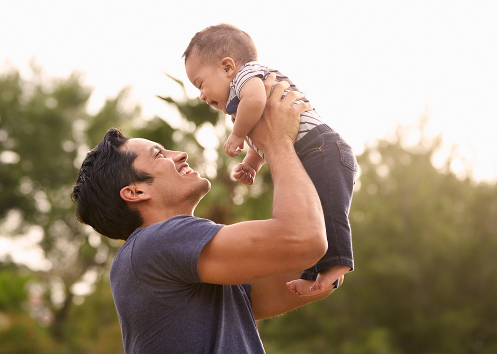 Father holding baby in park.