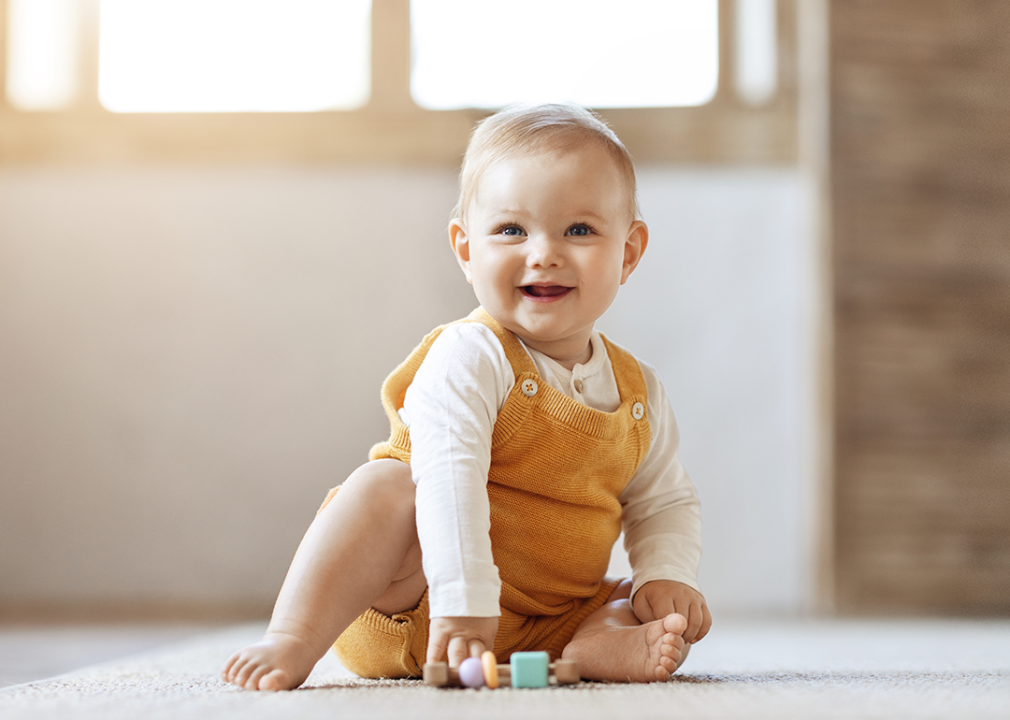 Baby sitting on floor playing with toys.