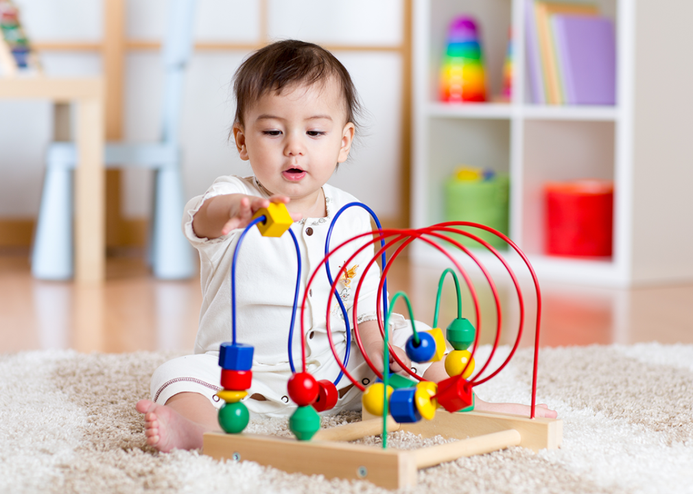 Baby playing with wooden toy in nursery.