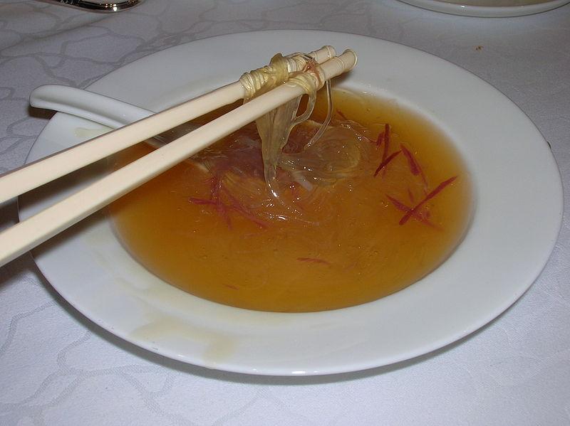 Close-up of a person eating bird's nest soup at a table.