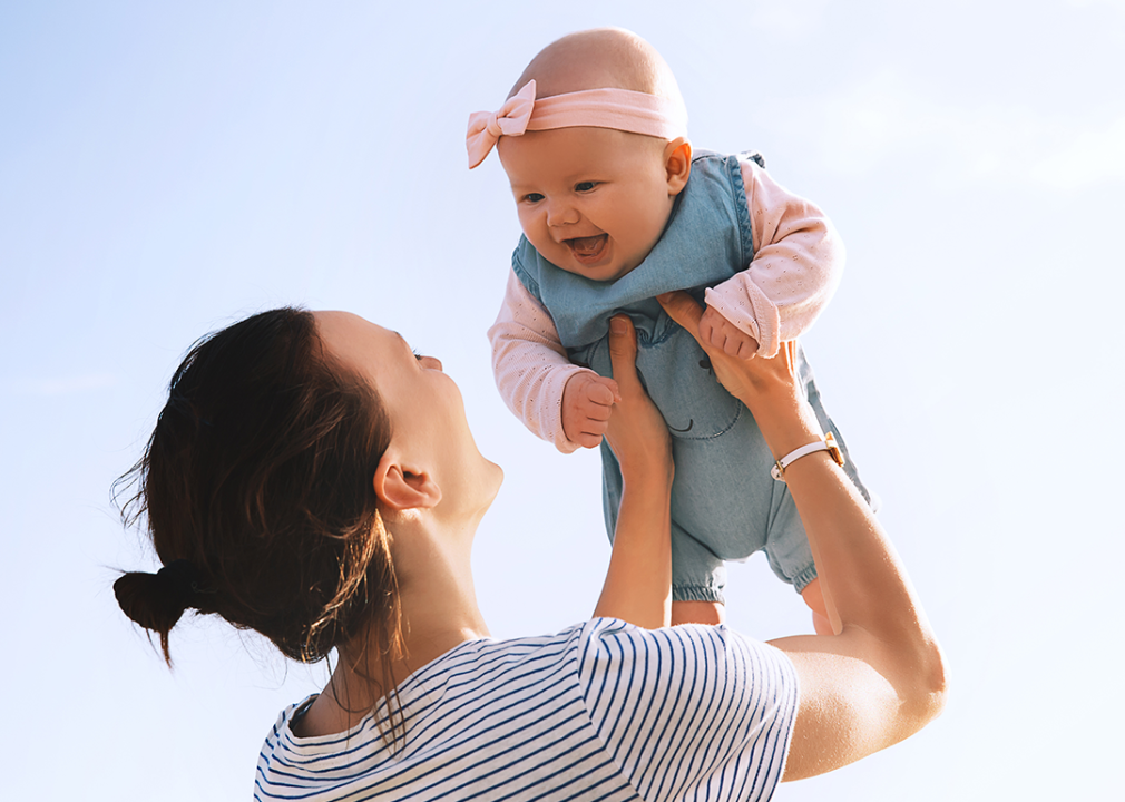 Mother holding baby up outside.