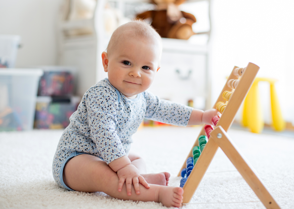 Baby sitting playing with abacus toy.