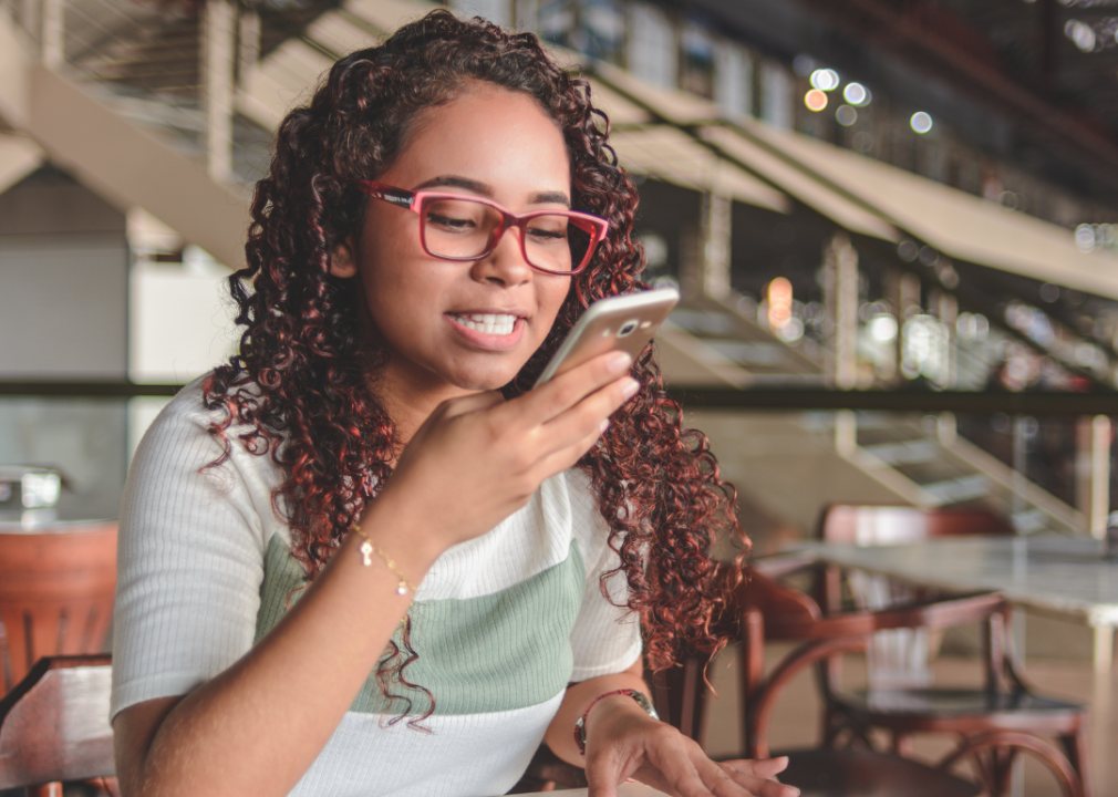 A woman speaking into the cell phone she is holding close to her mouth. 