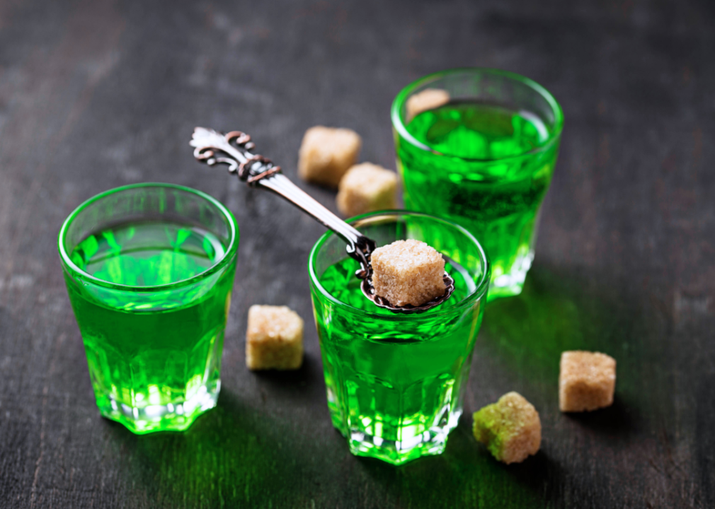 Three glasses of absinthe with brown sugar cubes.