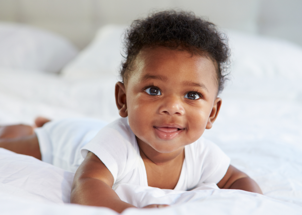 African American baby boy lying on bed.