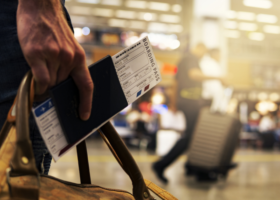 A man carrying a carry-on bag and boarding pass through an airport