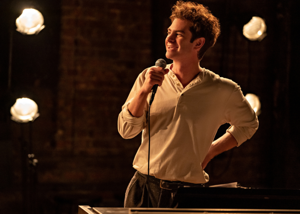 Andrew Garfield smiling and holding a microphone.