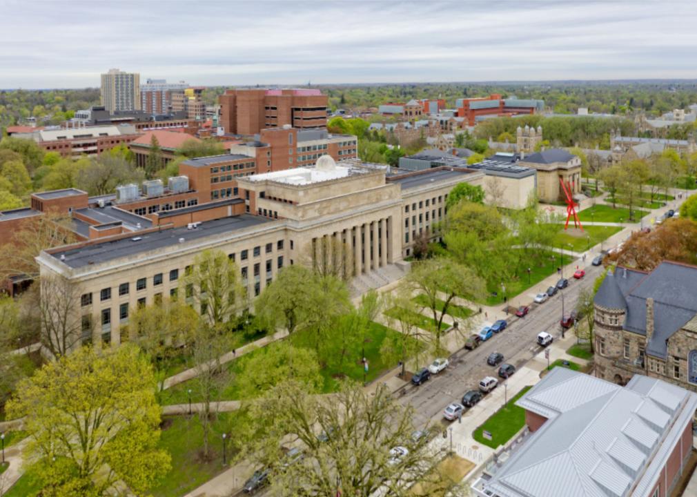 An aerial view of campus focused on a large gray building with columns and many windows.