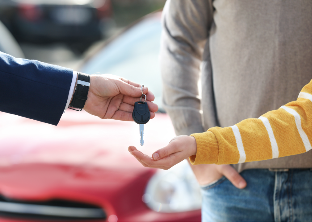 Salesman Giving Key to Customers in Modern Auto Dealership