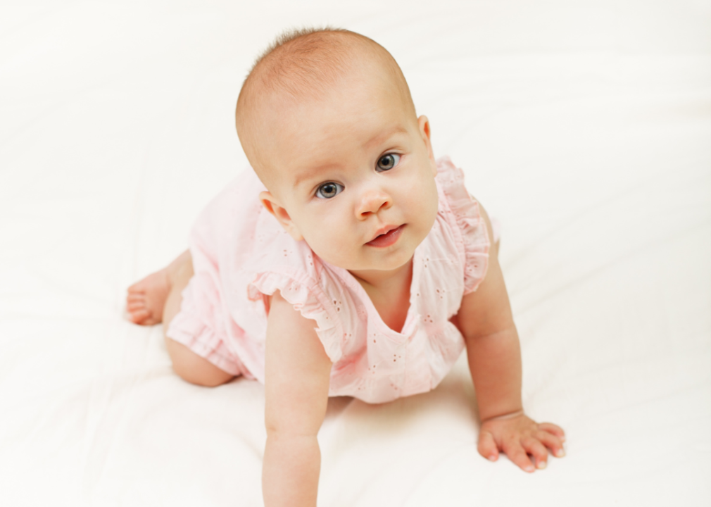 A closeup of a baby girl in pink summer dress looking up. 