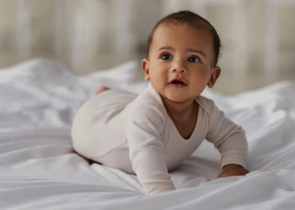 A baby lying on their stomach on a white bed.