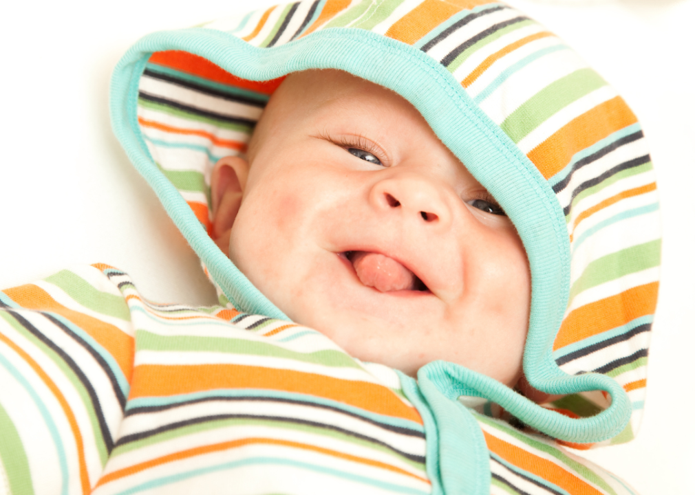A baby boy with wearing a colorful hood smiling. 