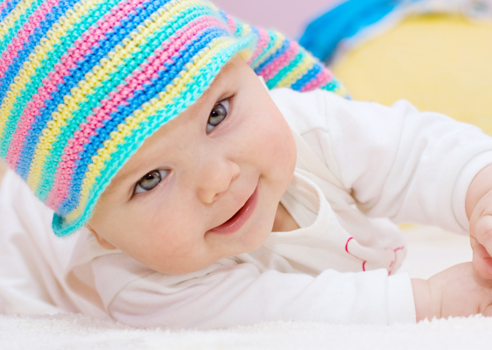 A closeup of a baby girl with blue eyes and colorful hat.