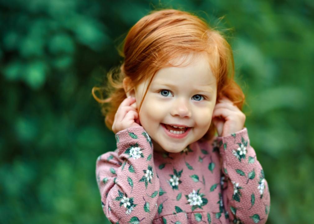 Red-haired little girl smiling happily.