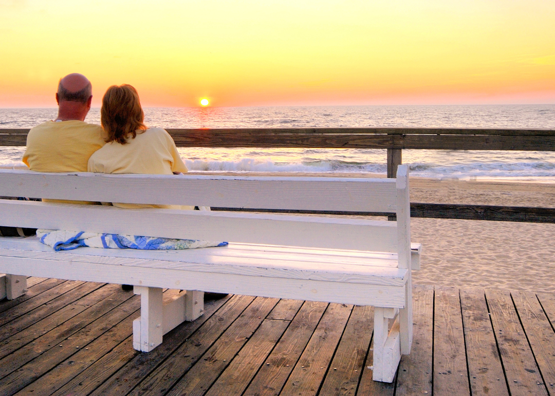 A couple watching the sunset on a bench at Bethany Beach.